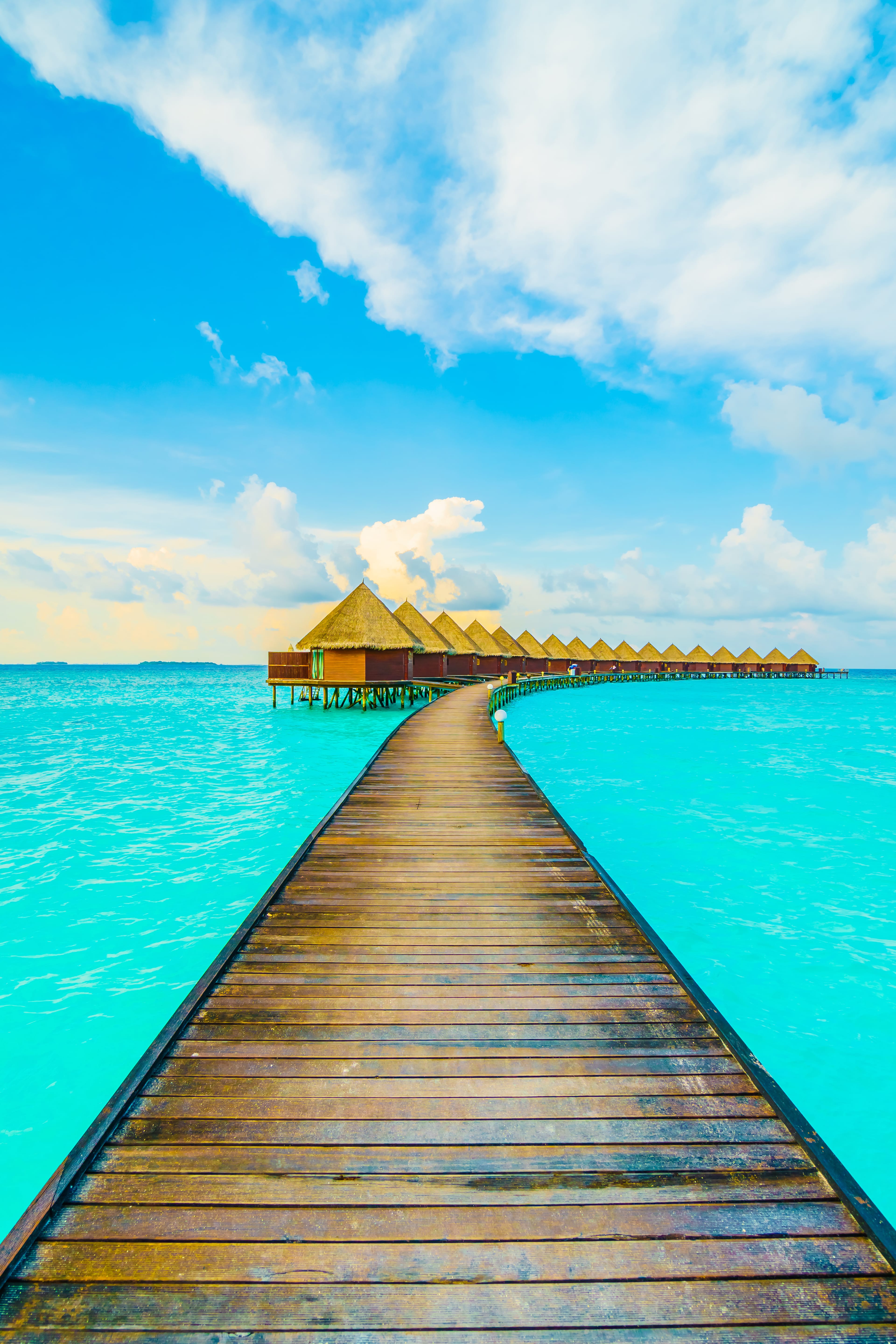 Wooden walkway to overwater villas in crystal clear turquoise waters